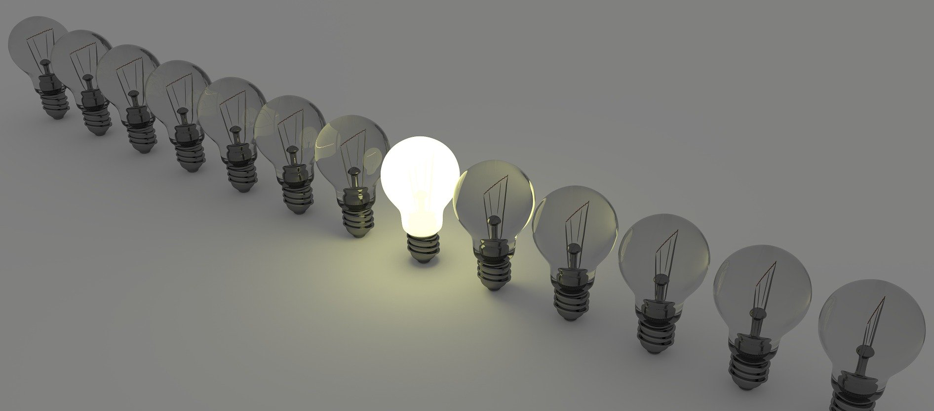 BrightIdeaBulbsRow Light bulbs standing in a row. Only one light bulb is brightly illuminated.
