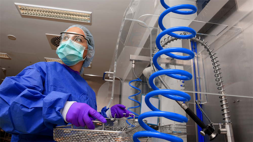 HospSterilization_247618456 A hospital sterilization professional in full PPE prepares medical instruments for cleaning.