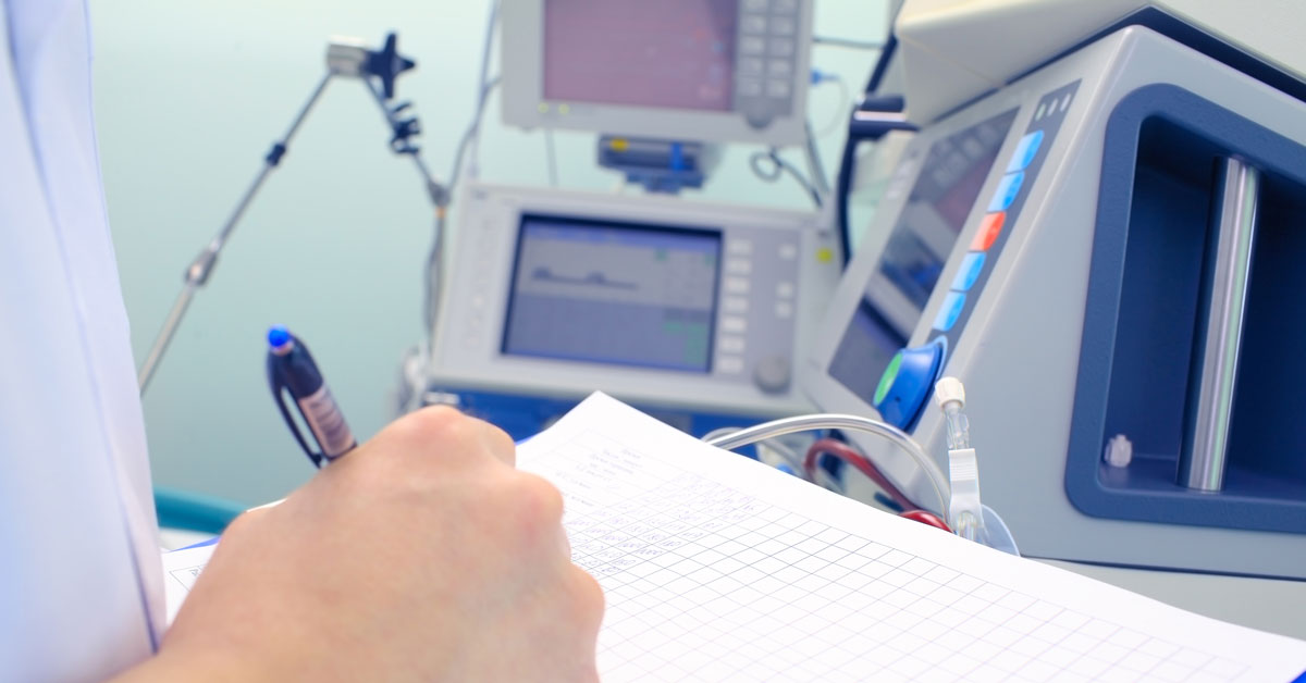 A person takes notes next to medical devices.