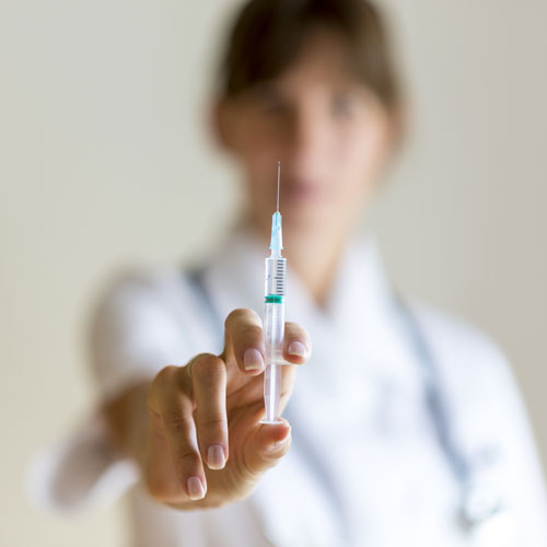 A doctor holds out a syringe full of a pharmaceutical 