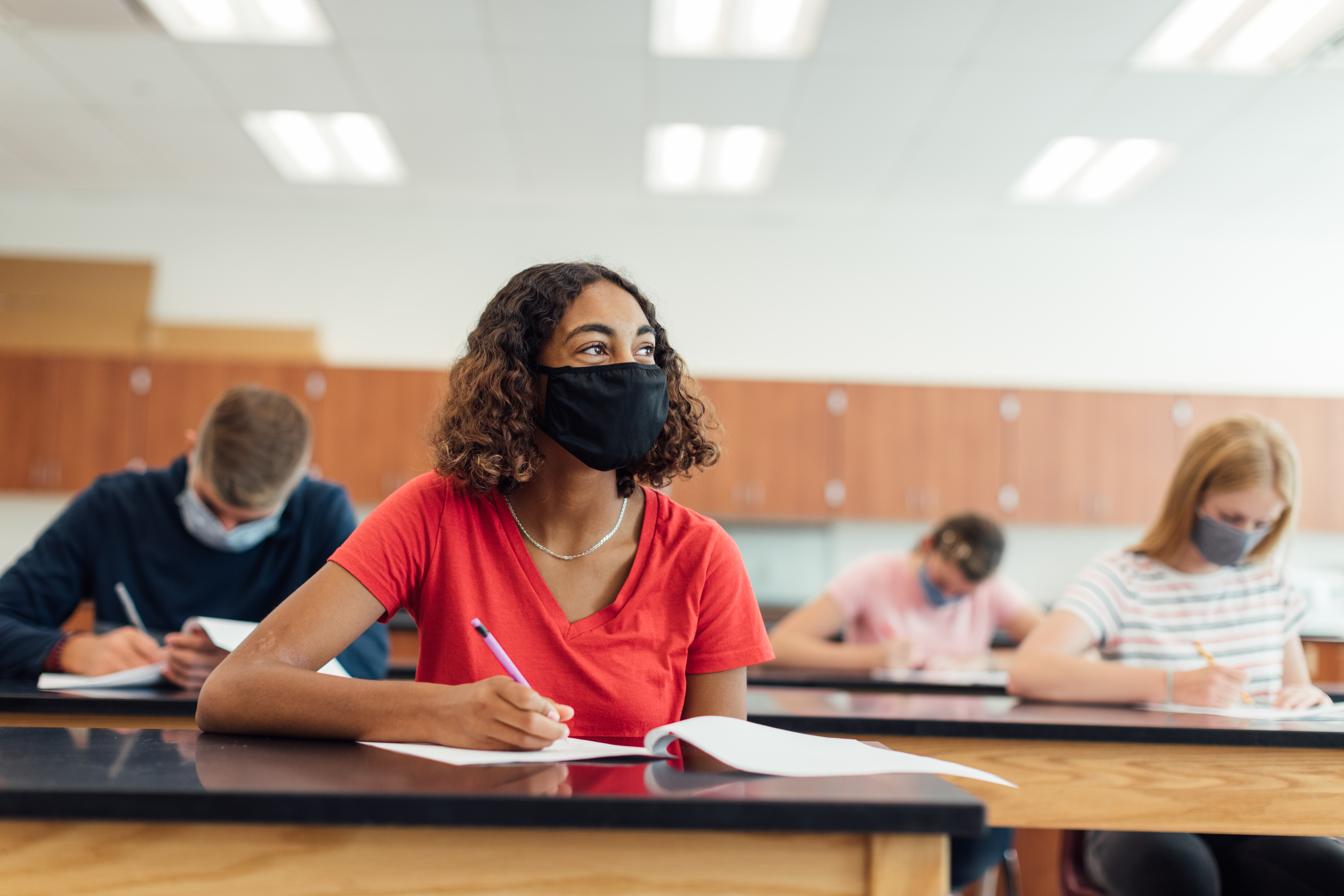 Applicants take a multiple choice test while wearing masks and practicing social distancing.