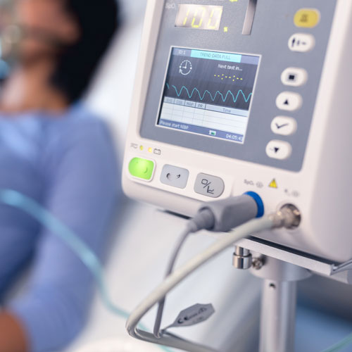 A ventilator operates next to a patient in a hospital.